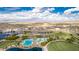Panoramic aerial view of a community featuring a pool, green spaces, and commercial establishments against a mountain backdrop at 17563 W Summit Dr, Goodyear, AZ 85338