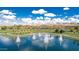 Scenic aerial view of a community lake with fountains, lush green lawns, and palm trees with mountains in the background at 17563 W Summit Dr, Goodyear, AZ 85338
