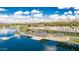 Aerial view of a lake featuring a dock and recreation center, with palm trees and mountains in the background on a sunny day at 17563 W Summit Dr, Goodyear, AZ 85338