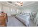 Bedroom featuring a ceiling fan, tray ceiling, wood dresser, and neutral paint at 17563 W Summit Dr, Goodyear, AZ 85338