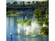 A serene view of the community lake, complete with water fountains, surrounding greenery, and a glimpse of the community clubhouse at 17563 W Summit Dr, Goodyear, AZ 85338