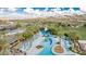 Aerial view of the community pool, deck chairs, waterslide and palm trees with mountains in the distance on a bright sunny day at 17563 W Summit Dr, Goodyear, AZ 85338