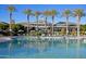 Large community pool with palm trees, lounge chairs, umbrellas, and a clubhouse at 17563 W Summit Dr, Goodyear, AZ 85338