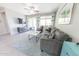 Well-lit living room with comfortable gray sofa, stylish rug and decor, with TV and ceiling fan at 17563 W Summit Dr, Goodyear, AZ 85338