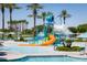 Colorful community splashpad with waterslides and other features; lounge chairs and palms abound at 17563 W Summit Dr, Goodyear, AZ 85338