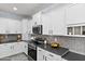 Modern kitchen with white cabinetry, gray backsplash, stainless steel appliances, and dark countertops at 1835 E Bartlett Pl, Chandler, AZ 85249