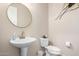 Stylish half bathroom features a pedestal sink, decorative mirror, and modern fixtures at 18406 W Verbena Dr, Goodyear, AZ 85338
