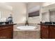 Elegant bathroom featuring a soaking tub, dual sinks, granite countertops, and picture window at 18406 W Verbena Dr, Goodyear, AZ 85338
