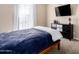 Well-lit bedroom with a navy blue comforter and TV at 18406 W Verbena Dr, Goodyear, AZ 85338