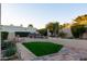 Landscaped backyard featuring a well-manicured lawn, colorful flower beds, and a charming outdoor dining area at 2548 E Vermont Ave, Phoenix, AZ 85016