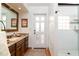Bathroom with a single vanity, granite countertop, door to the exterior, and walk-in shower with glass block window at 2548 E Vermont Ave, Phoenix, AZ 85016