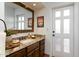 Bathroom with granite counters, wood cabinets, decorative mirror and a door to the exterior of the home at 2548 E Vermont Ave, Phoenix, AZ 85016