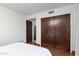 Bedroom featuring two dark wood closets, light walls, and hardwood flooring with a crisp white comforter at 2548 E Vermont Ave, Phoenix, AZ 85016
