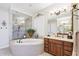 Bright main bathroom with a jacuzzi tub, a glass walk-in shower, and double vanities at 31626 N 129Th Dr, Peoria, AZ 85383