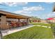 An outdoor bar with red cushioned stools sits on a manicured lawn and is perfect for backyard entertaining at 31626 N 129Th Dr, Peoria, AZ 85383