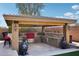 Covered outdoor kitchen with built-in grill, sink, and bar seating in a landscaped backyard at 31626 N 129Th Dr, Peoria, AZ 85383