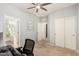 Neutral bedroom showing carpet, a ceiling fan, two white doors, and an attached bathroom on the left at 32405 N 23Rd Ave, Phoenix, AZ 85085