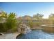 Backyard featuring a rock waterfall cascading into the pool with a view of the desert landscape at 3318 W Ravina Ln, Anthem, AZ 85086