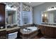 Bathroom with a soaking tub, dual vanities, decorative mirrors, and a privacy window at 3370 S Ivy Way, Chandler, AZ 85248