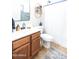 Well-lit bathroom featuring a wooden vanity, decorative mirror, and shower with a white curtain at 41250 W Thornberry Ln, Maricopa, AZ 85138