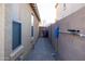 Narrow side yard featuring textured wall, windowed house exterior, and a gate leading to the backyard at 41250 W Thornberry Ln, Maricopa, AZ 85138