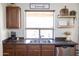 Close-up of the kitchen sink with wood cabinets, floating shelves, and a double basin stainless sink at 41250 W Thornberry Ln, Maricopa, AZ 85138