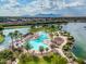 Aerial view of a resort-style pool surrounded by palm trees and a lake with mountain views at 42988 W Misty Morning Ln, Maricopa, AZ 85138