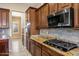 This kitchen features granite countertops, a gas cooktop, dark wood cabinets, and stainless steel appliances at 42988 W Misty Morning Ln, Maricopa, AZ 85138