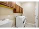 Well-lit laundry room featuring tile floors, ample storage cabinets, and a modern washer and dryer set at 42988 W Misty Morning Ln, Maricopa, AZ 85138