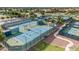 Aerial view of multiple fenced tennis courts with a covered shelter and well maintained landscaping at 42988 W Misty Morning Ln, Maricopa, AZ 85138