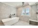 Bright bathroom with a soaking tub and a window with plantation shutters allowing natural light at 77 E Missouri Ave # 7, Phoenix, AZ 85012