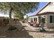 Landscaped backyard with mature trees, rock ground cover, and outdoor seating area at 8354 E Emelita Ave, Mesa, AZ 85208