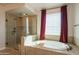 Relaxing bathroom featuring a soaking tub, separate glass-enclosed shower, and window with privacy blinds at 9729 E Theia Dr, Mesa, AZ 85212