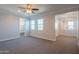 Bright bedroom showcasing large windows, a ceiling fan, plush carpeting, and an ensuite bathroom entrance at 9729 E Theia Dr, Mesa, AZ 85212