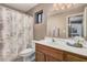 Well-lit bathroom featuring a single sink vanity with storage and a shower with floral curtains at 11525 E Laguna Azul Cir, Mesa, AZ 85209