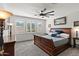 A spacious bedroom with natural light, carpet flooring, a ceiling fan, large bed, and decorative lamps on bedside tables at 12539 W Tuckey Ln, Glendale, AZ 85307