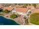 Aerial view showcasing a landscaped backyard with covered patio, fire pit, mature trees, and serene lake frontage at 1470 S Villas Ct, Chandler, AZ 85286