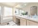 Clean bathroom featuring dual sinks, a soaking tub, and bright natural light at 1470 S Villas Ct, Chandler, AZ 85286