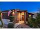 Inviting front entrance with a stained wood door, American flag, and desert landscaping at dusk at 16341 E Links Dr, Fountain Hills, AZ 85268