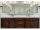 Bathroom featuring a double sink vanity, large mirror, and dark wood cabinetry at 18006 W Hess St, Goodyear, AZ 85338