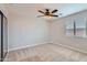 Carpeted bedroom featuring a ceiling fan, window, and a sliding door wardrobe at 23619 W Harrison Dr, Buckeye, AZ 85326