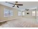 Expansive living room with neutral carpet, ceiling fans, and natural light from large windows at 23619 W Harrison Dr, Buckeye, AZ 85326