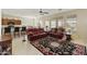 Open-concept living area featuring tile floors, ceiling fan, and comfortable red seating, seamlessly connected to kitchen at 24822 S Sedona Dr, Sun Lakes, AZ 85248