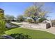 Landscaped backyard with artificial turf, mature trees, and stone path with outdoor oven and BBQ at 28604 N 92Nd Pl, Scottsdale, AZ 85262