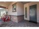 Inviting front porch with seating area, stylish brickwork, and a modern front door at 4876 N 206Th Ln, Buckeye, AZ 85396