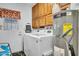 Bright laundry room includes side by side washer and dryer with overhead wood cabinets at 5141 E Elena Ave, Mesa, AZ 85206