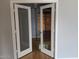 Close up of open glass french doors with white trim leading to a room with wooden blinds and hardwood flooring at 5501 S Dove Crk Crk, Buckeye, AZ 85326