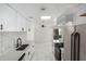 Bright kitchen features white cabinetry, stainless steel appliances, and a stylish backsplash with a view to the living room at 6767 N 7Th St # 212, Phoenix, AZ 85014