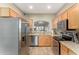 Efficient kitchen with stainless appliances, wood cabinets, and a view into the living room at 7021 E Earll Dr # 223, Scottsdale, AZ 85251