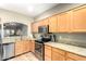 Well-lit kitchen with stainless steel appliances, wooden cabinets and breakfast bar looking into the living area at 7021 E Earll Dr # 223, Scottsdale, AZ 85251